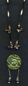 Necklace with lime green and black circular pendant with bells and glass.