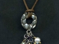 Necklace on cord with silver color disc and faux pearl and crystal dangles.