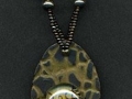 Necklace with gold and black oval pendant with glass.