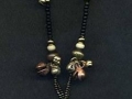 Necklace with lime green and black circular pendant with bells and glass.